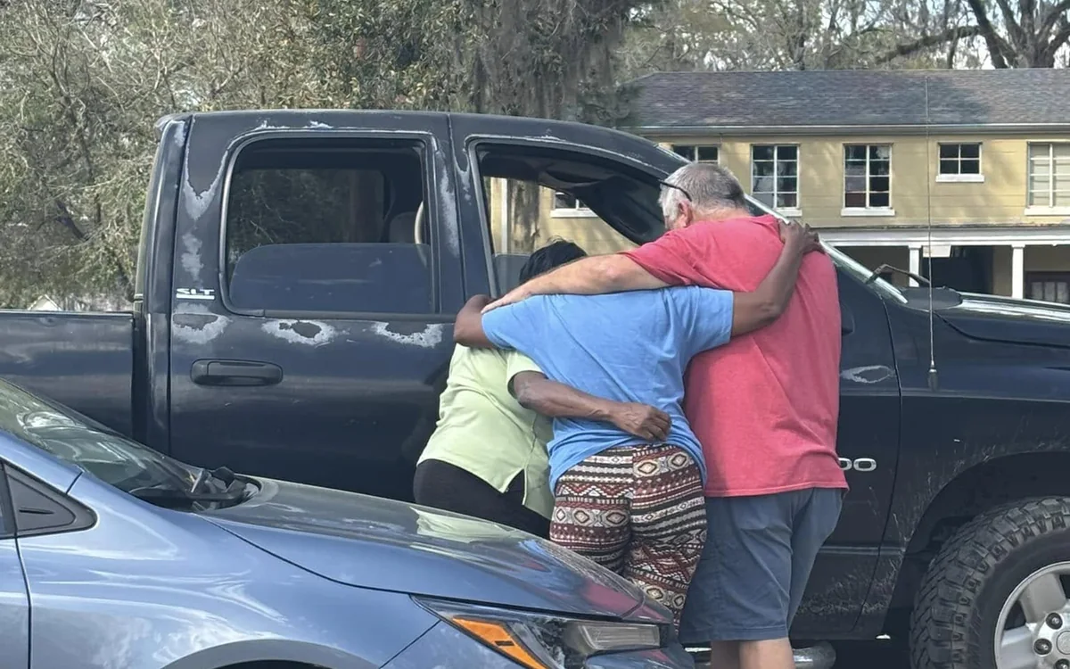 Church members sharing a hug and prayer with a neighbor outside